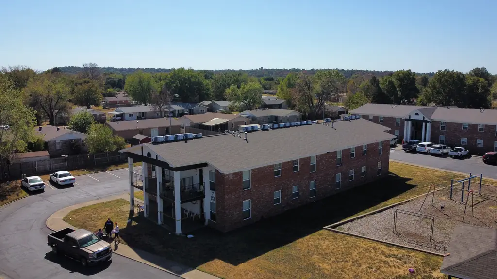 Aerial view of a two-storey brick apartment building with a new grey shingle roof and rooftop equipment