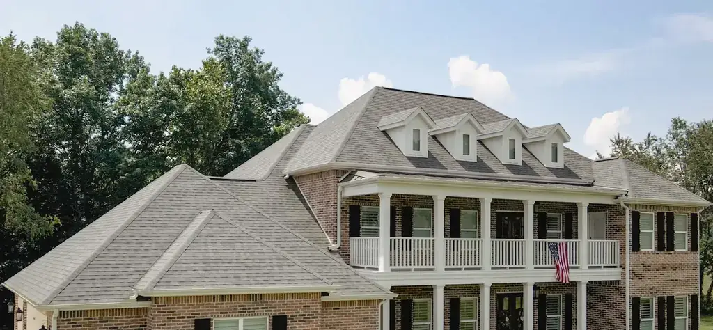 Brick colonial with a white double porch and a new grey roof, seen from a drone at roof height