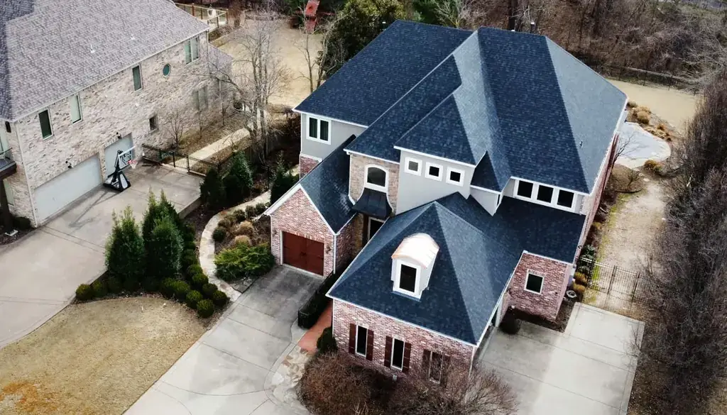 Drone view of a brick and stucco home with a new blue-grey shingle roof