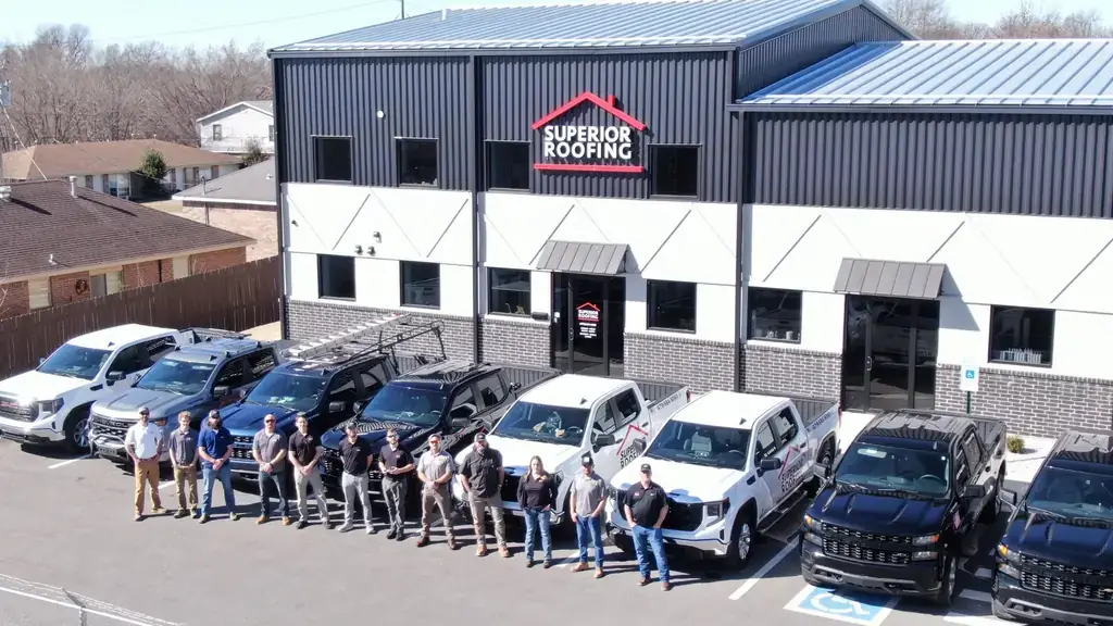 The Superior Roofing crew lined up in front of the Springdale shop and a row of branded white and black pickups